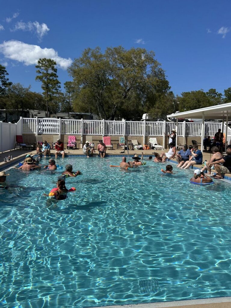 Guests swimming in the heated pool at Sandy Oaks RV Resort